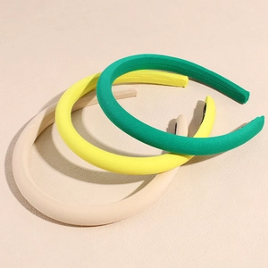 Tre cerchietti in spugna colorati in verde, giallo e beige per donne alla moda