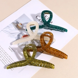 Grandi mollette per capelli in acrilico verde e ambra con trama geometrica su una rivista