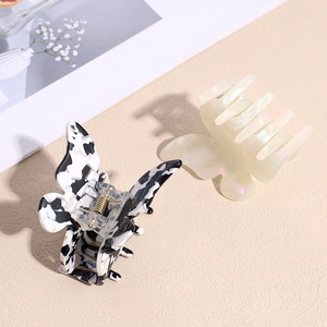 Iridescent butterfly hair claws in marble and pearl white finishes on warm background