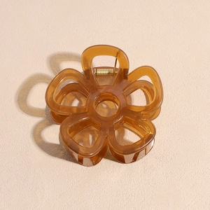 Detail of amber brown resin flower hair claw clip with golden metal spring and hollow design