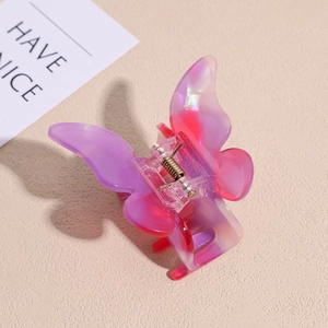 Detailed macro view of pearlescent butterfly hair claw with gradient pink resin and metal spring