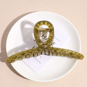 Dettaglio macro della grande molletta per capelli in ambra acrilica con trama geometrica