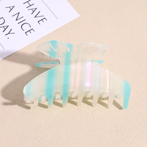 Macro shot of iridescent butterfly hair claw with light blue stripes on beige background