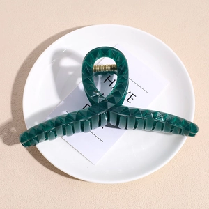 Dettaglio del fermaglio per capelli verde scuro trasparente con trama geometrica