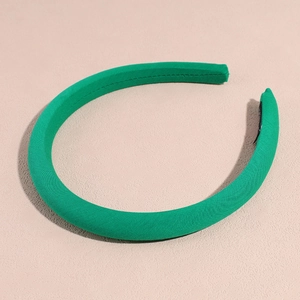 Dettaglio ravvicinato di un cerchietto imbottito verde che mostra la trama del tessuto