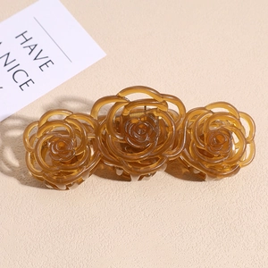 Detail view of large amber resin hair claw clip with three carved roses pattern
