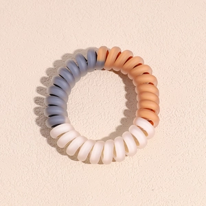 Détail macro d'élastiques spirales tricolores avec une texture plastique mate dépolie