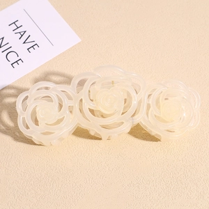 Detail view of large cream resin shark hair claw clip with triple rose flower pattern