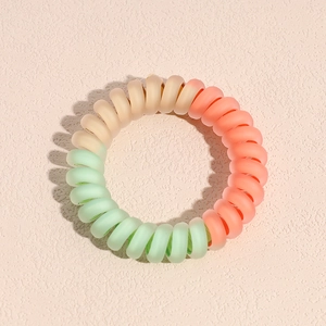 Détail d'un élastique spirale mat dégradé en rose pêche, beige et vert menthe clair