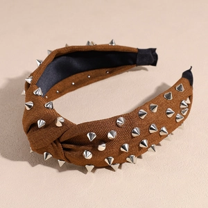 Détail d'un serre-tête en tissu marron avec des rivets argentés et un nœud élégant