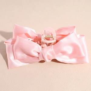 Détail de la grande pince à cheveux nœud en satin rose montrant la texture du tissu