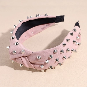 Gros plan du serre-tête noué rose orné de rivets métalliques argentés décoratifs
