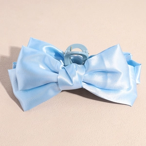 Détail de la pince à cheveux en ruban de satin bleu clair montrant la texture du tissu