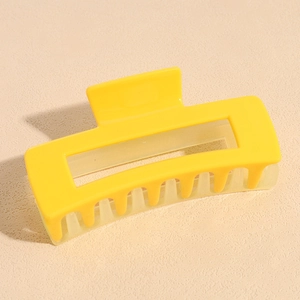 Détail macro d'une pince à cheveux rectangulaire jaune vif avec des dents mates
