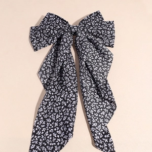 Dettaglio del fiocco per capelli nero a fiori con lunghi nastri in chiffon leggero