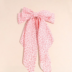 Dettaglio di un fermaglio per capelli con fiocco floreale rosa e nastri lunghi eleganti
