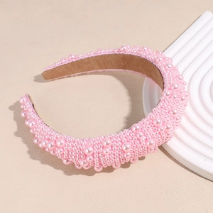 Detail eines pinkfarbenen gepolsterten Stirnbands mit Barockperlen und braunem Wildleder