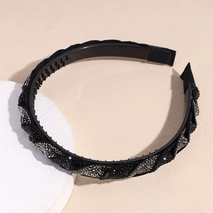 Dettaglio del cerchietto intrecciato con strass neri e denti antiscivolo per capelli