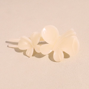 Gros plan sur l'élégante pince à cheveux papillon en acrylique beige au fini brillant