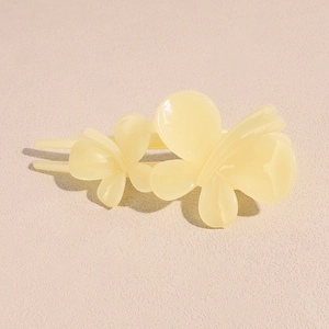 Détail de la pince à cheveux papillon jaune crème avec finition en résine brillante et ailes