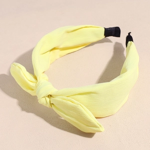 Detailed close-up of light yellow chiffon bow headband with black non-slip protective ends