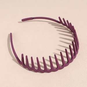 Serre-tête ondulé violet foncé avec dents sur un fond beige minimaliste