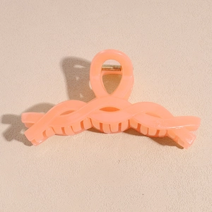 Detail view of large peach hair claw clip with a twisted weave design and matte finish