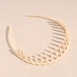 Détail d'un serre-tête ondulé beige avec dents antidérapantes sur fond texturé