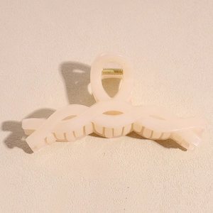 Detail of matte cream claw clip with textured twist handle and gold metal spring