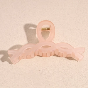 Close-up of a large matte pink shark hair claw clip with a hollow twisted design