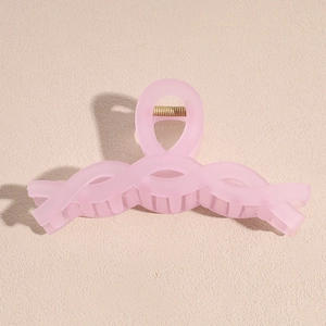 Detail of pink matte large hair claw clip with crossed wave design and golden spring