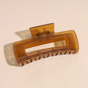 Close-up of a hollow rectangular amber resin shark hair claw with metal spring detail