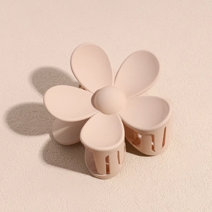 Gros plan d'une pince à cheveux fleur rose nude mat avec cinq pétales ronds et dents