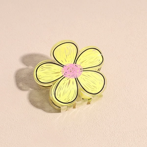 Dettaglio del fermaglio per capelli a fiore in acrilico giallo con bordi dipinti