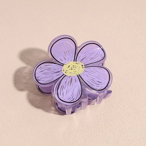 Primo piano di una pinza per capelli a fiore viola in acrilico con bordi neri dipinti
