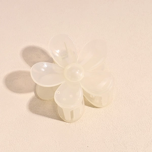 Detail of flower-shaped cream hair claw clip with semi-transparent resin and metal spring
