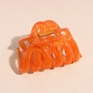 Détail de la grande pince à cheveux orange avec texture translucide et ressort doré