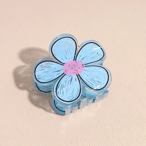 Dettaglio di un fermaglio per capelli a forma di fiore blu in acrilico su base beige
