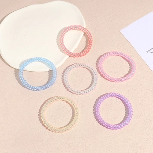 Set di sei elastici per capelli a spirale iridescenti in colori pastello su sfondo neutro