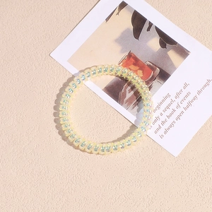 Dettaglio macro dell'elastico a spirale giallo traslucido con finitura perlata su beige