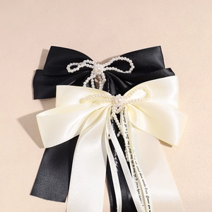 Close-up of elegant satin bow hair clips with pearls and decorative printed ribbons