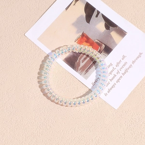 Dettaglio macro di elastico a spirale per capelli con glitter olografici e riflessi iridescenti