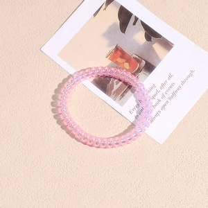 Dettaglio dell'elastico a spirale con finitura olografica cangiante rosa e viola