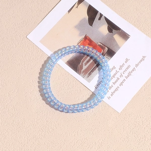 Dettaglio dell'elastico a spirale blu iridescente su una carta decorativa bianca