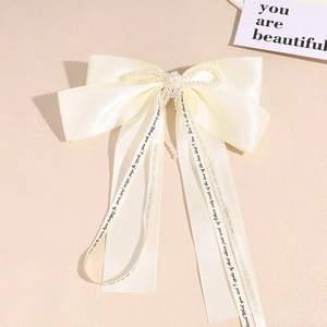 Detail of cream satin bow hair clip with pearl flower and printed poetry ribbons