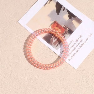 Dettaglio dell'elastico a spirale con finitura perlata scintillante in rosa e arancione