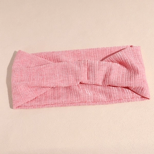 Détail d'un bandeau de yoga rose à rayures verticales avec un design à nœud central