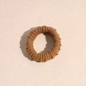 Dettaglio di un elastico per capelli marrone a coste su una superficie in pietra