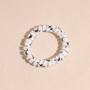 White spiral telephone cord hair tie featuring a black star pattern for ponytails