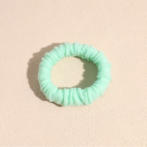 Primo piano di un elastico per capelli verde menta con morbido tessuto a pieghe